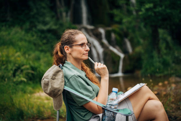 Lady biologist contemplating by the waterfall