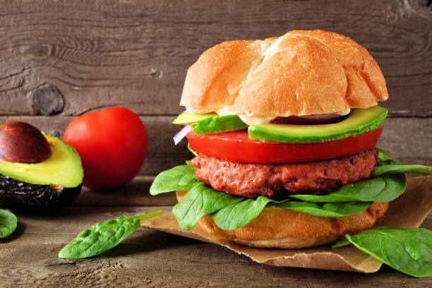 istock Plant based meatless burger with avocado, tomato and spinach against a wood background 1159908613