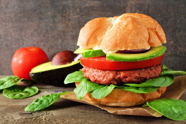 istock Plant based meatless burger with avocado, tomato and spinach against a dark background 1159908637