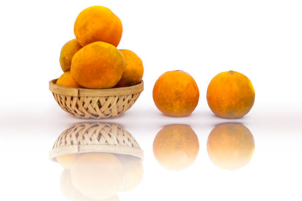 Fruit basket full of raw organic fresh oranges isolated on white along with reflection.