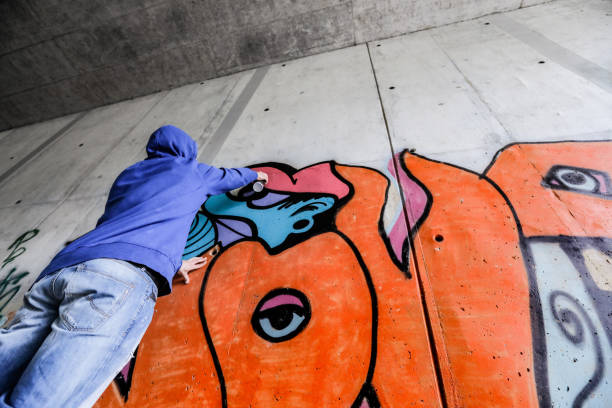 Unrecognizable Person Drawing Colorful Grafitti in Highway Underpass.