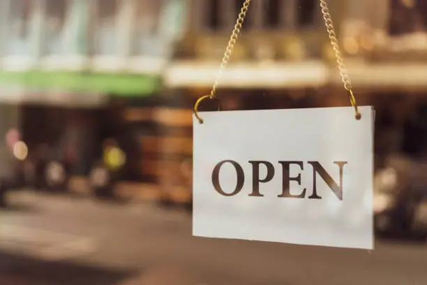 Photo of A business sign that says Open on cafe or restaurant hang on door at entrance. Vintage color tone style.