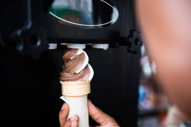 istock Human hand holding cone with twisted ice cream from machine 1159925220