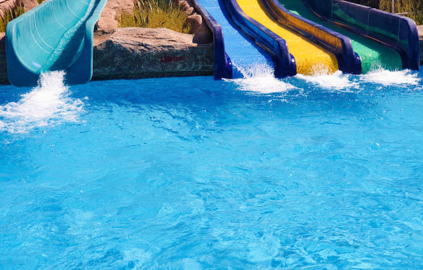 istock Multi-colored water slides with water jets in the blue pool 1159927383