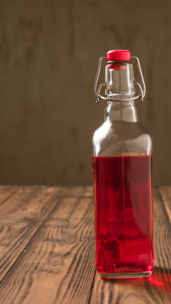 istock Glass bottle with plum alcohol on a wooden table. 1159929249