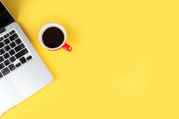 istock top view of simple business office table with workspace laptop computer and red coffee cup on yellow background with right copy space 1159932692