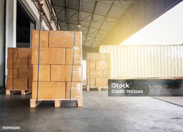 Warehouse Cargo Courier Shipment Stack Of Cardboard Boxes On Wooden Pallet And Truck Docking At Warehouse Stock Photo - Download Image Now