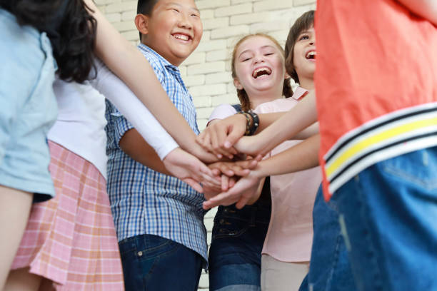 istock group of school kids stacking hands in classroom (education concept) 1159937262