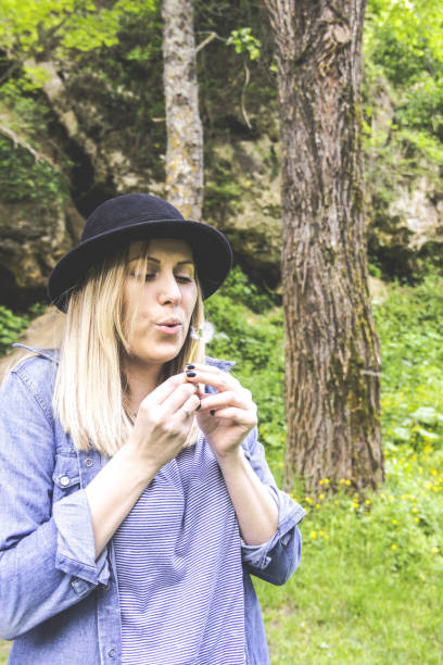 istock Girl blowing on white dandelion in the forest 1159941521