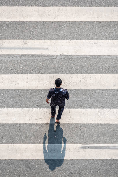 Young chinese man walking on a zebra crossing stock photo