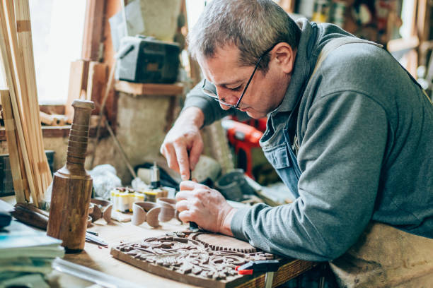 istock Carpenter in his workshop carving wood with chisel 1159944553