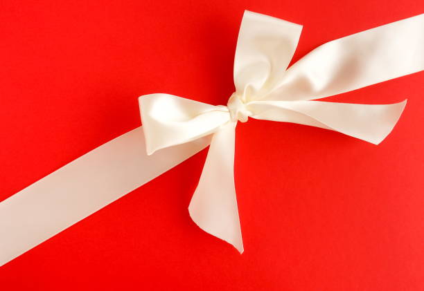 istock white satin ribbon on red background. top view. copy space 1159944762