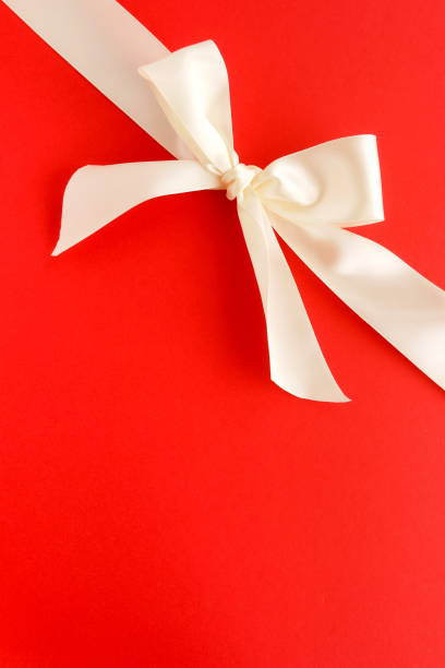 istock white satin ribbon on red background. top view. copy space 1159945367