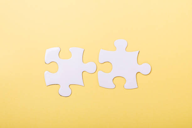 istock Two disconnected jigsaw puzzle pieces on yellow background White puzzle Concept success of business 1159945408