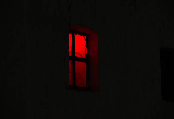 istock Window with burning red light in the night dark 1159946280