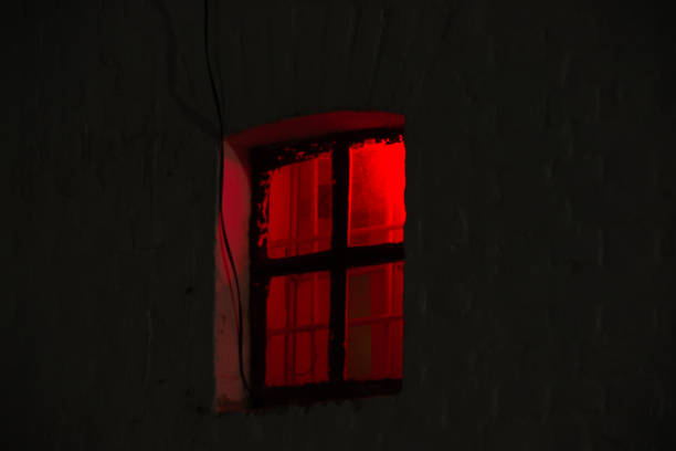 istock Window with burning red light in the night dark 1159946283