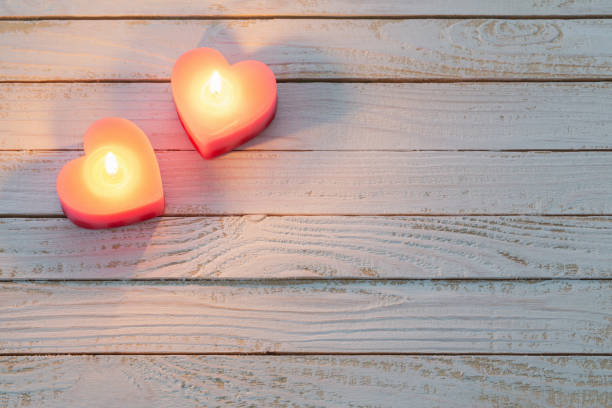istock pink burning candles on white wooden background 1159947400