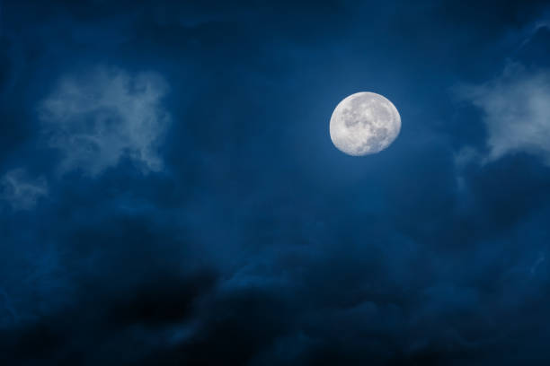 Lua na noite com as nuvens brilhantes e escuras no fundo azul - foto de acervo