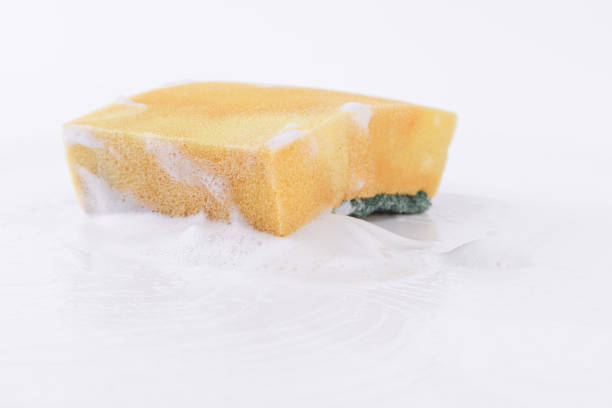 Old dish-washing sponge full of foam on a white background