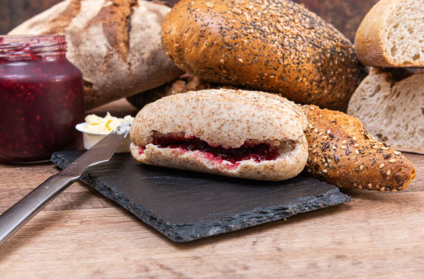 istock Bread with jam. Loaf of bread with jam on a black slate 1159950934