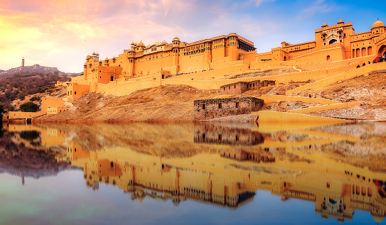 Historic Amber Fort Jaipur Rajasthan at sunset with mirror reflection as seen on the adjoining lake. Amber Fort or Amer Fort is a UNESCO World Heritage site.