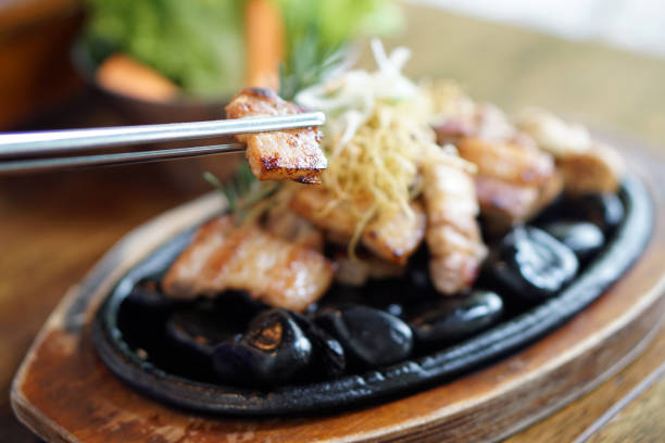 The photo shows frozen spiced pork being grilled on a hot grill.
