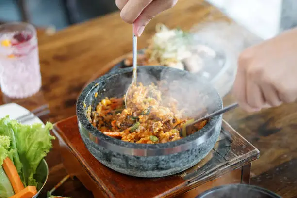 Photo of Dolsot bibimbap - Korean mixed rice, Include steamed rice, vegetables, pork and fried egg on top, served in a hot stone pot, Dolsot means stone pot in Korean.