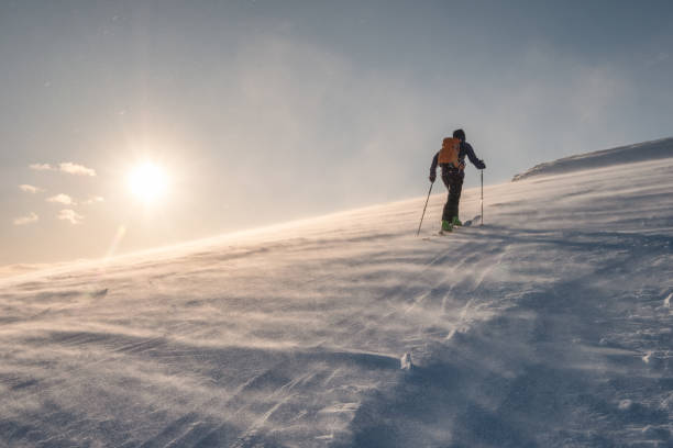 istock Skier with backpacker hiking on snow hill at sunset 1159960093