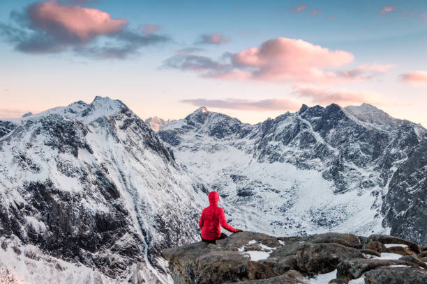 istock Red mountaineer relaxing on rock with magnificent mountain at evening 1159960098
