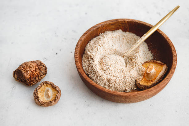 rowder wird aus chinesischen getrockneten pilzen shiitake in einer holzschüssel auf einem tisch hergestellt. das konzept des medizinischen zusatzstoffes für gesunde lebensmittel. - shiitake mushroom edible mushroom mushroom dry stock-fotos und bilder