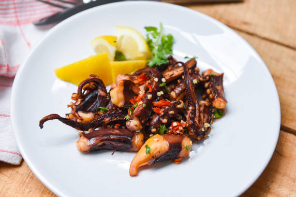 istock Octopus salad with lemon herbs and spices on white plate / Tentacles squid grilled appetizer food hot and spicy chilli sauce seafood cooked 1159961155