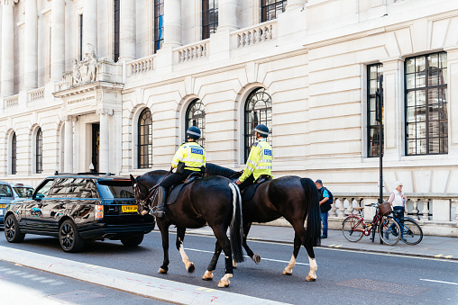 London, UK - May 15, 2019: English Police officers mounted on horseback patrolling near Whitehall in Westminster