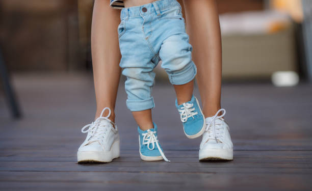 the first steps of the baby with the help of mom - shoe women adult baby imagens e fotografias de stock