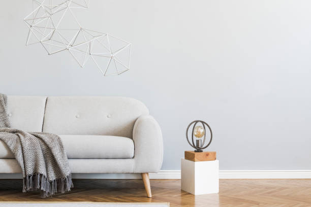 istock Minimalistic and stylish interior of open space with design gray sofa, coffee table, lamps, pillow. Gray background walls, brown wooden parquet. Modern concept of room. Template. Copy space. 1159966565