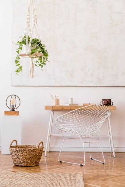 istock Minimalistic boho interior with design and handmade macrame shelf planter hanger for indoor plants, wooden desk, armchair, lamp, white cube and elegant accessories. Stylish home decor. White walls. 1159966933