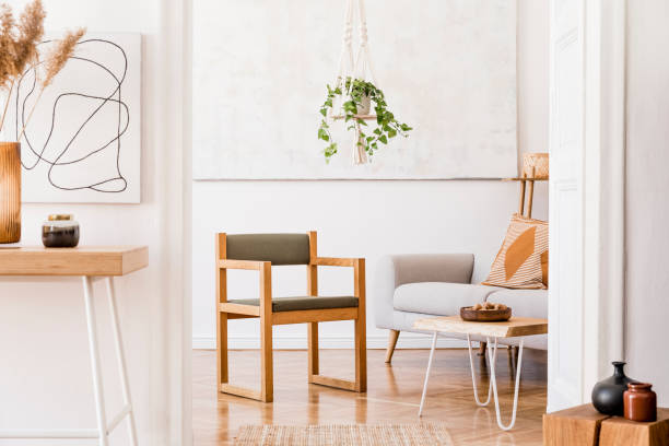 istock The nice boho open space interior at cozy apartment with design gray sofa, wooden desk, armchair and coffee table, plants and elegant accessories. Mock up poster on the white wall. Stylish home decor. 1159967039