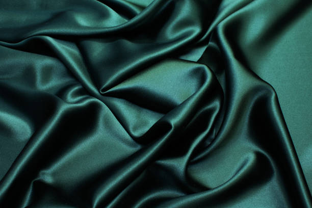 istock Silk fabric, satin. The color is dark green. Texture, background, pattern. 1159968456