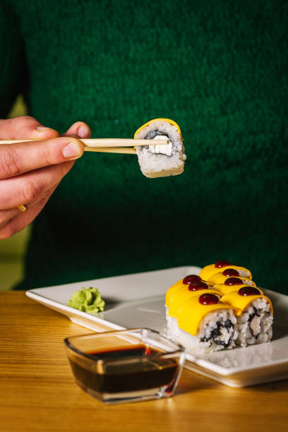 istock Men's hands hold sushi with chopsticks over plate 1159969805