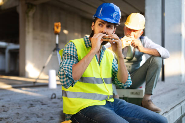 istock Happy young and senior engineer worker sitting at building site on break 1159972109