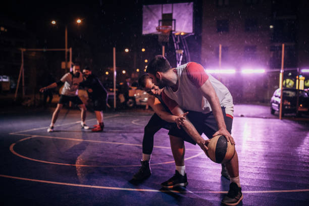istock Four guys playing streetball at night 1159974115