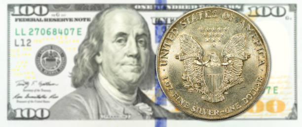 istock one silver dollar coin against 100 us-dollar banknote obverse 1159979480