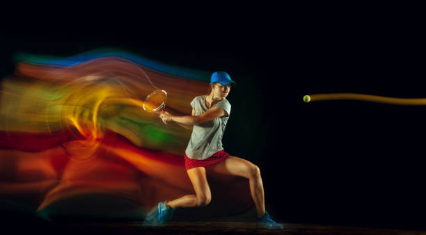 One caucasian woman playing tennis on black background in mixed light