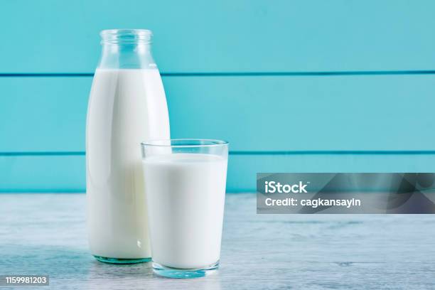 Bottle Of Milk And A Glass Full Of Milk On A Wooden Table Against Turquoise Wooden Background Close Up View Stock Photo - Download Image Now