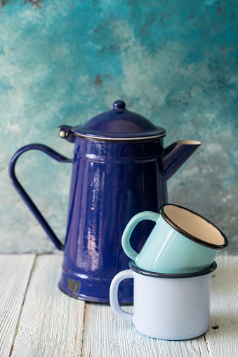 enameled blue tea pot and mugs on a wooden table