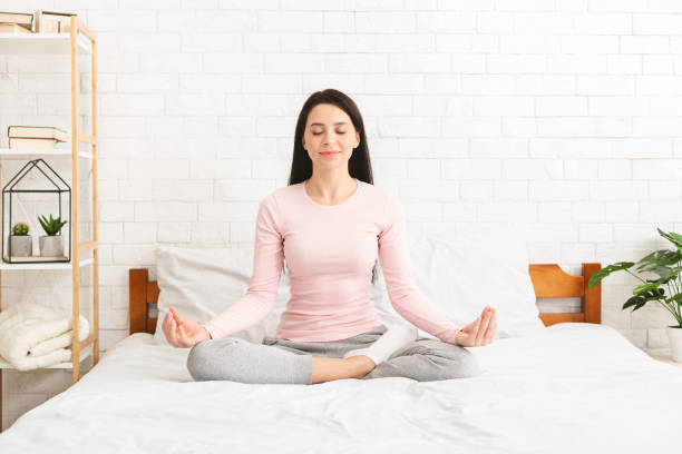 istock Young caucasian woman practicing yoga in bed 1159988052