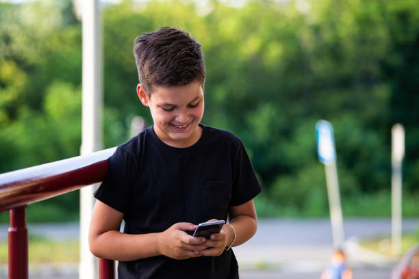 istock Smiling boy using mobile phone, Kid texting on his smart phone and laughing 1159988302