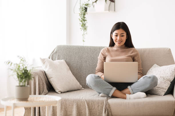 chicas buscando oportunidades de trabajo en línea en el ordenador portátil - laptop women sofa internet fotografías e imágenes de stock