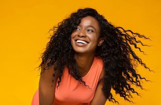 Youth and happiness. Young african woman laughing on yellow background