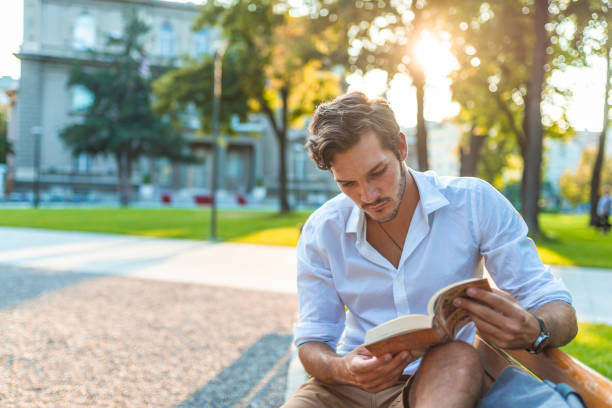 istock Young man reading book in park copy space 1159989099
