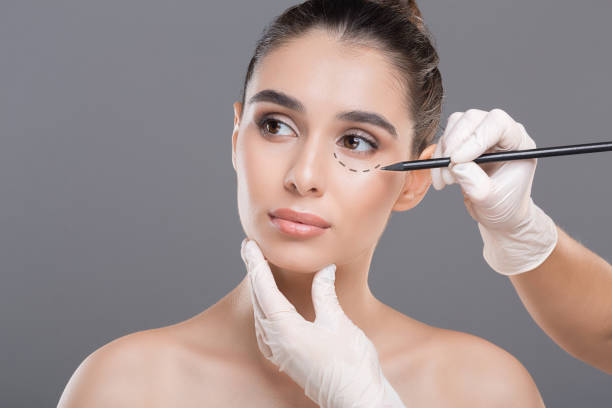 istock Surgeon drawing marks on female face against gray background 1159989109